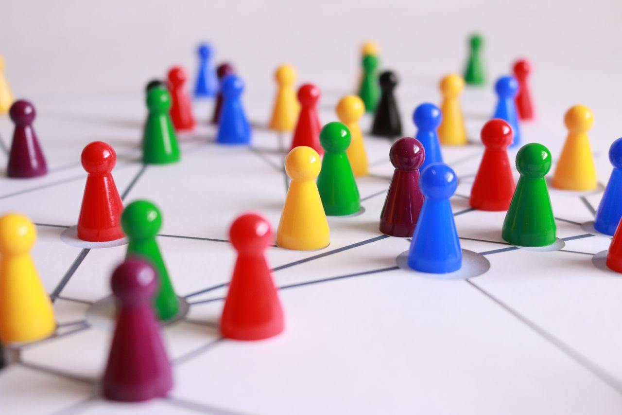 About A strategic arrangement of colorful pawns connected on a game board, symbolizing networking and teamwork.